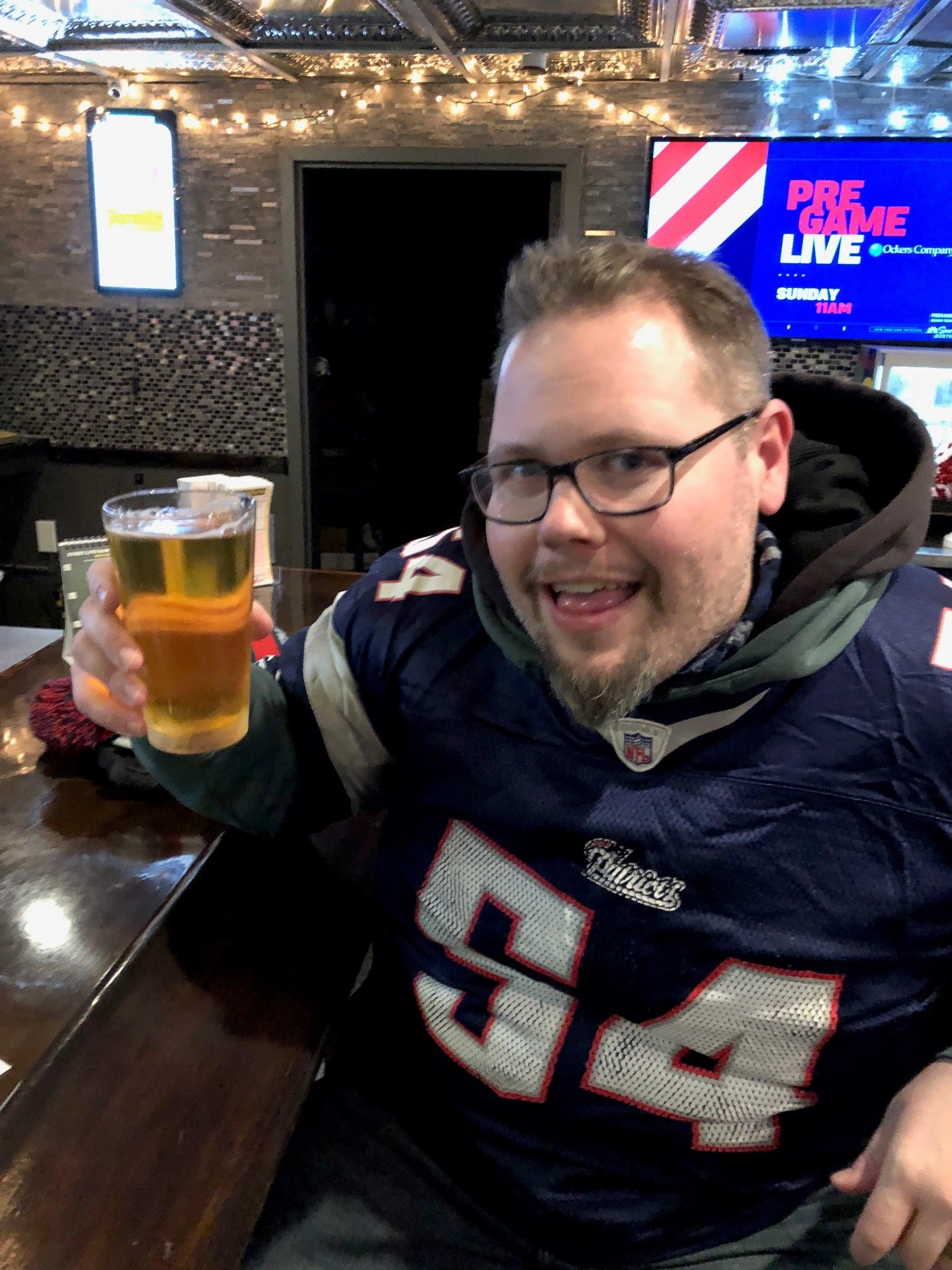 Ryan raising a beer while wearing a Patriots jersey